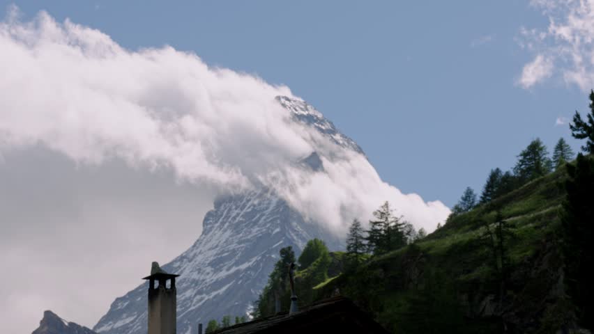 Dramatic clouds swirling around the iconic matterhorn peak in the swiss alps on a bright sunny day
