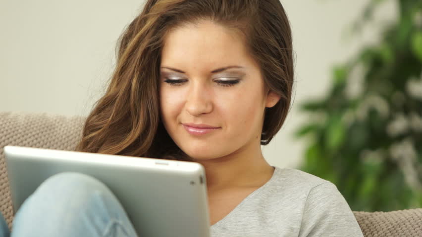 Young adult with touchpad looking at window and smiling
