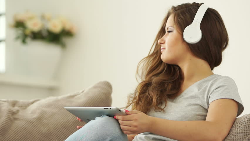 Young adult enjoying music and holding tablet

