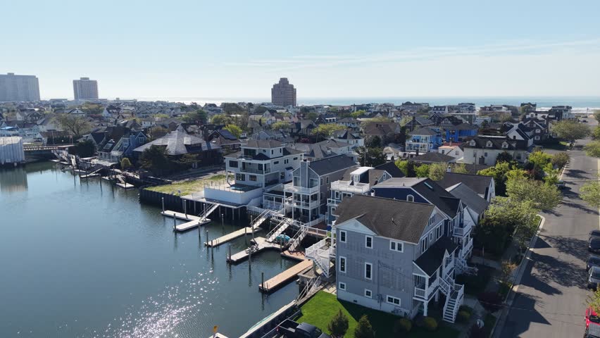 Elevating reveal drone view of a snooth bay with houses and boat slips revealing a beach town and ocean on the other side of the island