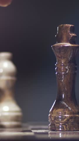 Cinematic slow motion close-up of one chess piece capturing another as the dark chess piece falls dramatically. Perfect for illustrating strategy, competition, decision making, tactics, victory, defeat, and intellectual gameplay.