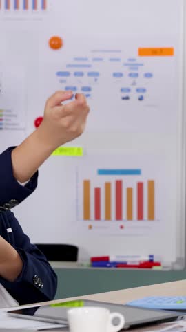 Young boy in business suit gestures confidently while working at a desk with laptop.