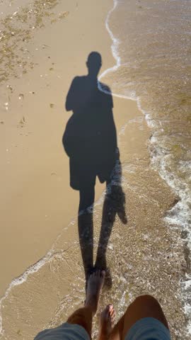 The shadow of a man walking along a sandy beach towards the sea. Baltic Sea, Poland