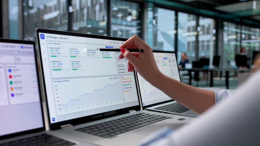 Marketing Manager Analyzes Online Ad Campaign Performance Using Multiple Computer Screens.
