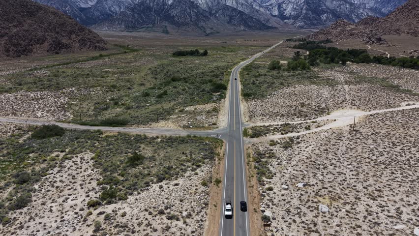 Cinematic aerial drone footage traveling above a remote road through Alabama Hills with the Eastern Sierra Mountains in the distance, California, USA, captured in 4K.
