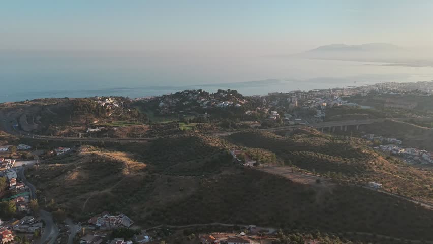 Aerial panorama of Malaga, Spain, featuring coastal hills, residential areas, and the Mediterranean shoreline, blending urban development with scenic natural landscapes.