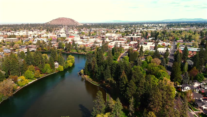 Wide Aerial Panorama of City With Butte and Surrounding Forest Visible From Above
