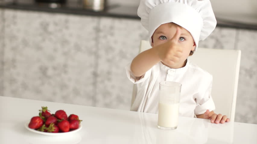 Little boy with strawberries and milk showing thumbs up
