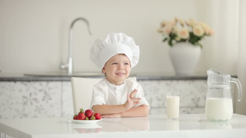 Little boy chef sitting at table and smiling
