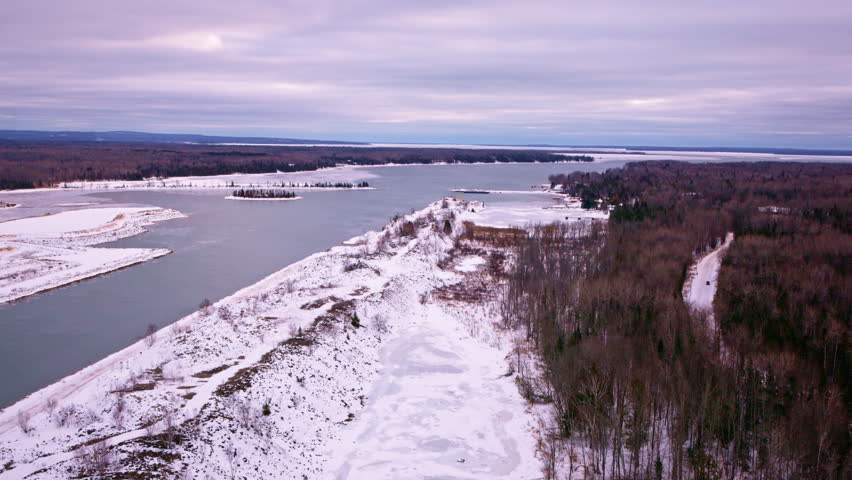 Drone shot overlooking a partially ice-covered Lake Superior bay with a quiet winter landscape below.