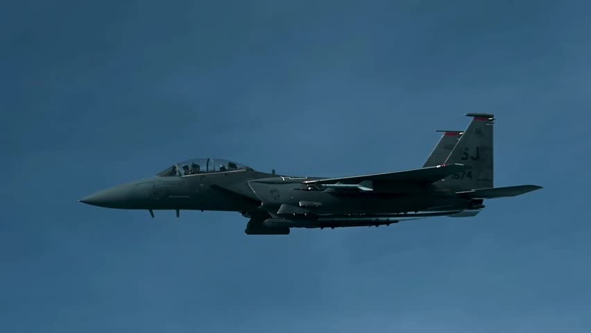 U.S. Air Force Boeing F-15E Strike Eagle twin-seat multirole fighter aircraft flying in level flight against a clear blue sky. High-quality military aviation footage showcasing the powerful combat jet, advanced air superiority capabilities, precision strike platform, and modern aerospace technology.
