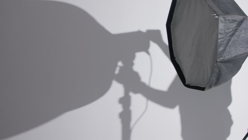 A  grayscale shot of a man in silhouette setting up his camera lights