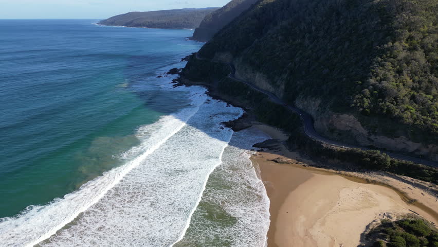 Drone panorama of Great Ocean Road Australia featuring coastal mountains rolling hills and highway beside the Southern Ocean in Victoria