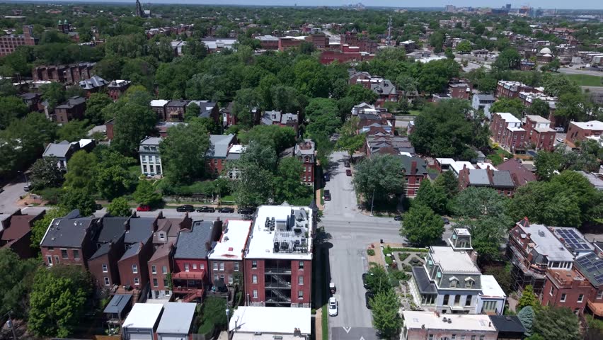 Lush green historic St. Louis residential neighborhood in Missouri revealing red brick homes, apartment buildings, and treetops - low altitude forward aerial flyover