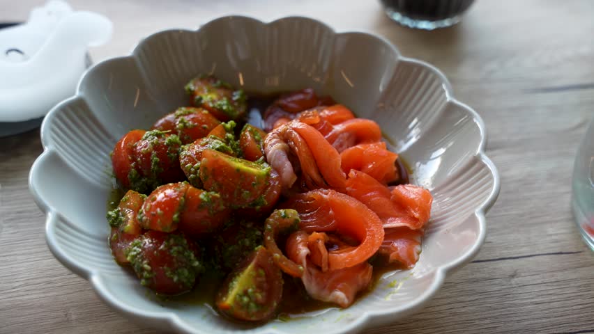 Close-up of rainbow trout sashimi served with tomato pesto in a restaurant setting, showcasing fresh ingredients, gourmet presentation and contemporary cuisine