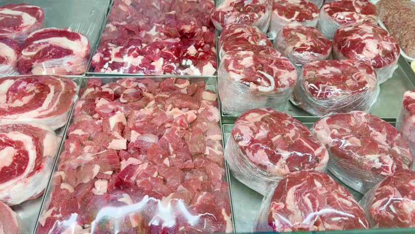 Fresh Meat Display at a Grocery Store Counter.Glass-Topped Refrigerated Meat Counter with Various Cuts of Meat in a Supermarket