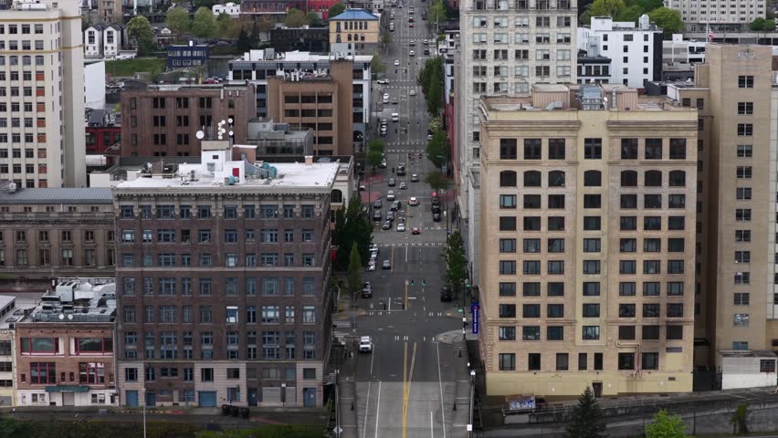 Classic early-1900s masonry office buildings line long straight avenue, where steady traffic flows through Tacoma
