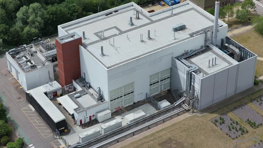 Aerial view of a large white technology research center building in a green setting. A semi-truck is parked at a loading dock during the day.