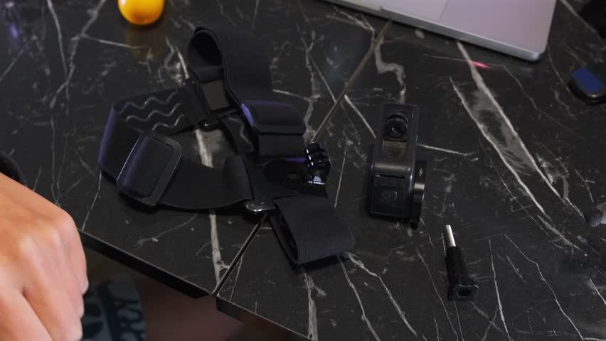 female hands attaching head mount to action camera close-up, securing strap and tightening connector for filming, practical setup process for recording and wearable camera use