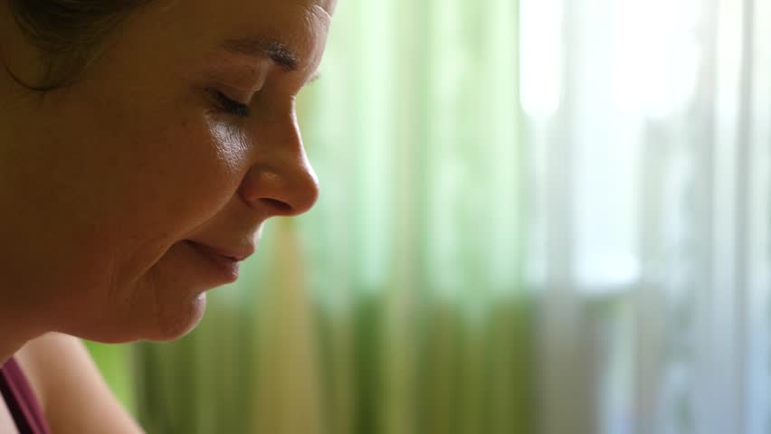 Close up of a woman eating ice cream in a waffle cone while enjoying a cold sweet dessert indoors.