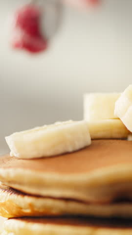 In the kitchen, a cook arranges fresh raspberries on a stack of golden pancakes on a plate, preparing fruit and berry pancakes tomorrow. A large pancake and raspberry plan