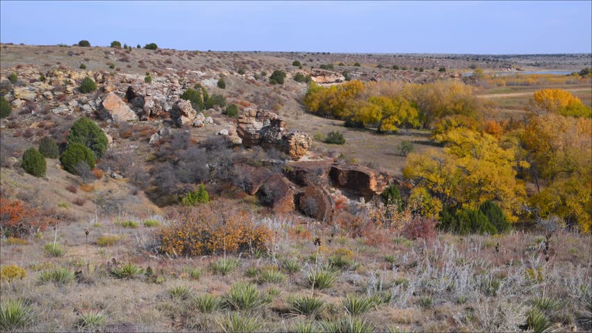 Landscape in Black Mesa State Park and Nature Preserve, Oklahoma, USA, renowned for its unique volcanic rock formations and the convergence of Great Plains prairie ecosystems. The depicted area corresponds to the Archeological Canyon and Rocky Garden Loop Trail, a popular hiking route offering panoramic canyon views, sandstone rock shelters, rugged geological outcrops, and native prairie vegetation.