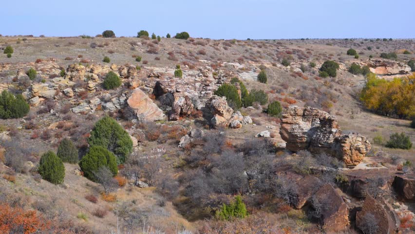 Landscape in Black Mesa State Park and Nature Preserve, Oklahoma, USA, renowned for its unique volcanic rock formations and the convergence of Great Plains prairie ecosystems. The depicted area corresponds to the Archeological Canyon and Rocky Garden Loop Trail, a popular hiking route offering panoramic canyon views, sandstone rock shelters, rugged geological outcrops, and native prairie vegetation.