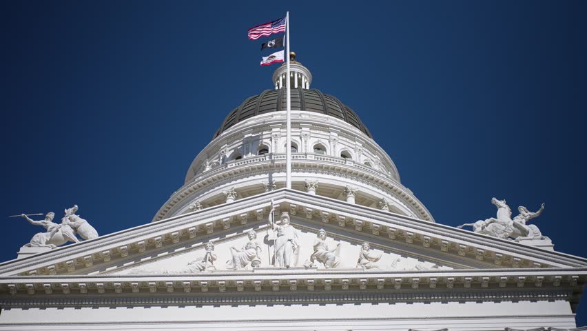 Walking around the California State Capitol in Sacramento with clear skies and bright sunlight shining on the building.