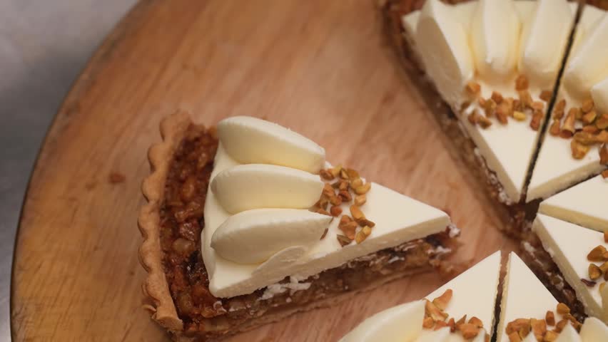 Close-up of a professional pastry chef wearing black nitrile gloves carefully slicing a decadent caramel nut tart. The gourmet dessert features a buttery crust, rich caramel nut filling, and is elegan