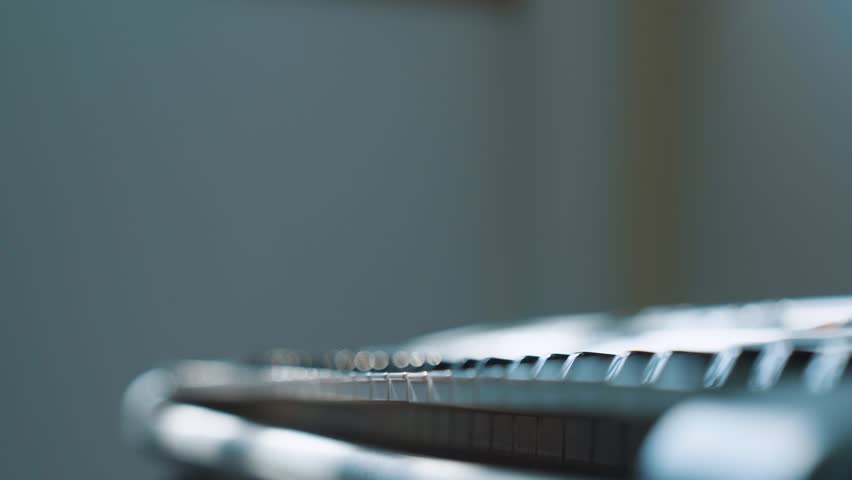 Close-up of hands playing an electronic keyboard with soft natural light and shallow depth of field.