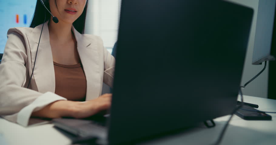 Young Asian female agent talking on phone headset consulting client online in call center office. Corporate customer service, technical support, remote tech operator, business team help desk concept.