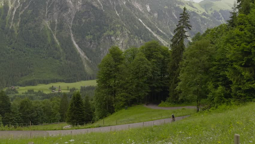 Cyclist on a drop bars road bike enjoying an epic ride and scenic cycling route on a winding paved mountain road through beautiful alpine valleys of Oberstdorf in Bavarian Alps destination