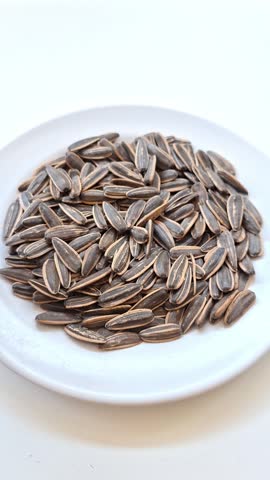 Brown skin hands picking a sunflower seed and cracks the hulls, vertical video, first person point of view
