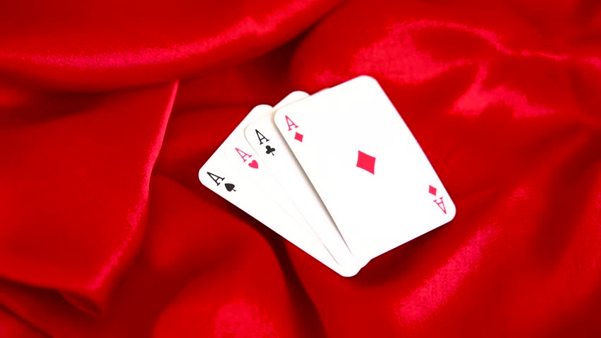 Four aces playing cards arranged in a fan on red silk fabric background poker game gambling casino