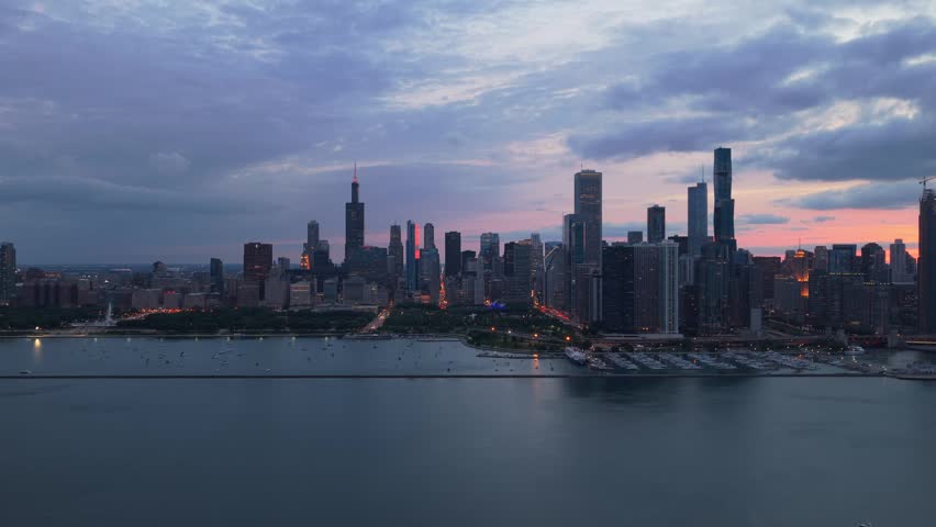 Elevated urban panorama of downtown Chicago skyline showcasing famous skyscrapers like Willis Tower and modern architecture with Lake Michigan during summer sunset