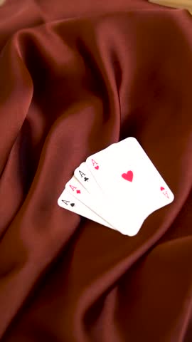 Fan of four ace playing cards displayed on dark brown silk cloth aces poker gambling casino luck