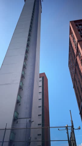 A low-angle, vertical video capturing the stark concrete architecture of the BT telecommunication Tower in Birmingham, West Midlands, England.