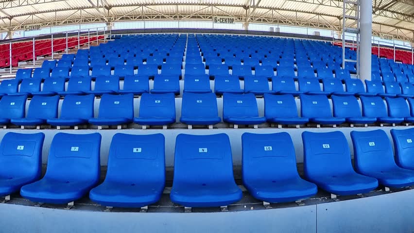 Empty sports stadium seating under roof filmed with cinematic 4K camera movement.
