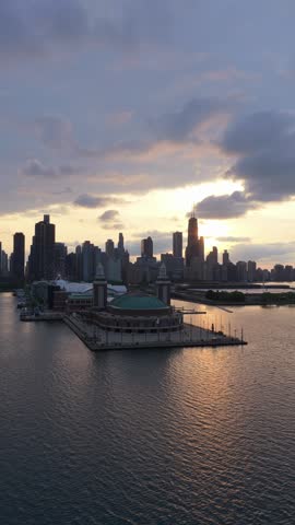 Golden hour sunset reflecting on Lake Michigan with Chicago skyline, Navy Pier, John Hancock Center creating urban silhouette against warm sky background