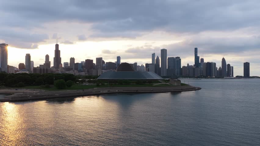 Chicago skyline over Lake Michigan at sunset with sunlight reflecting on water and showing prominent landmarks including Willis Tower and Shedd Aquarium