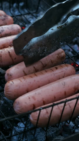 Vertical video. Summer barbecue, cookout. Grilling sausages during summer picnic