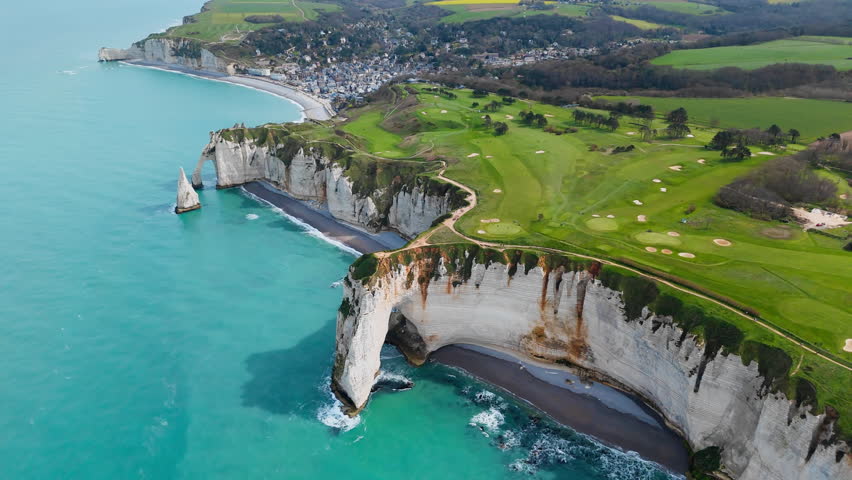 Etretat cliffs and rocky coastline on English Channel, northern France. Drone footage of landmark limestone formations and coastal travel destination