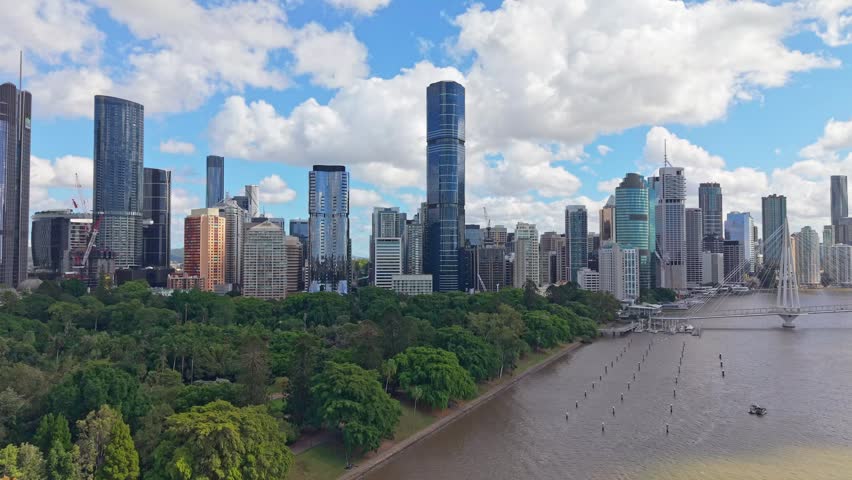 Brisbane city skyline overlooking the Brisbane River and Kurilpa Bridge beneath dramatic clouds on a bright afternoon in Queensland.