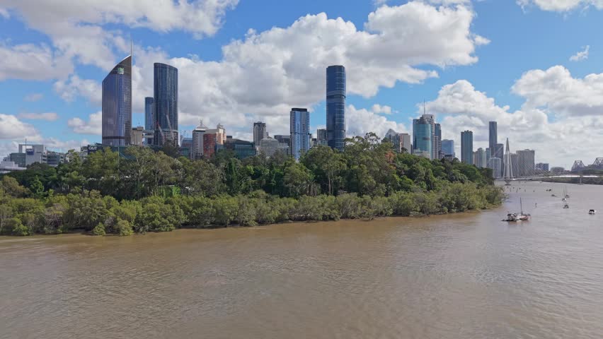 Brisbane city skyline overlooking the Brisbane River and Kurilpa Bridge beneath dramatic clouds on a bright afternoon in Queensland.