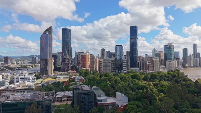 Brisbane CBD skyline rising above the City Botanic Gardens beneath dramatic clouds on a bright day in Queensland, Australia.