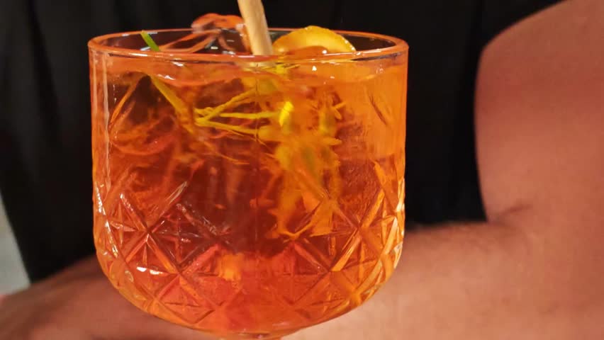 glass with orange cocktail. Stirring ice with fruit in a glass with an aperol cocktail
