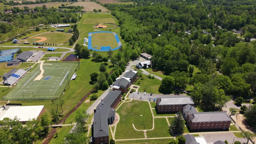 Aerial view of a college campus in Brevard, North Carolina, showcasing buildings, sports fields, and green spaces in a vibrant landscape