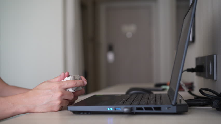 Closeup people hand or gamer holding joystick or gaming controller to enjoy playing game on computer notebook or laptop console and clenching fist or fistful victory fun and win satisfy with joy stick