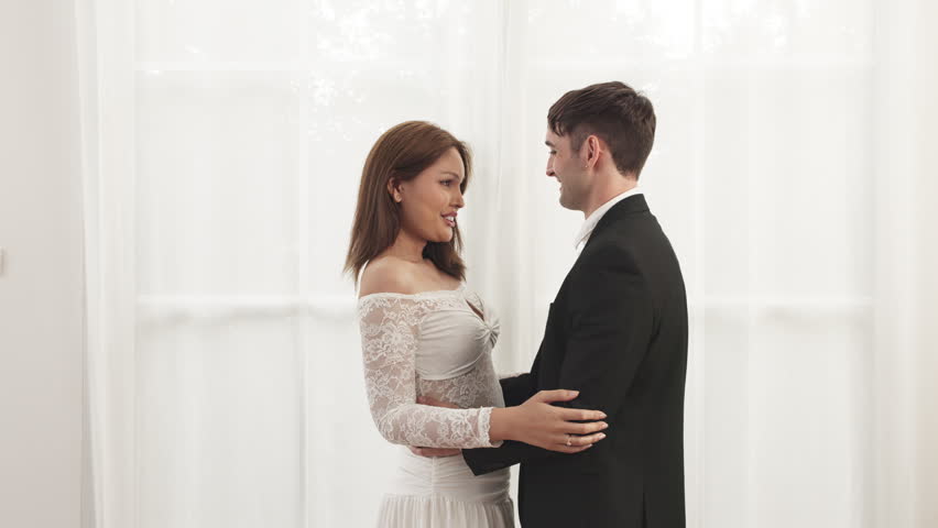 Bride and groom share a tender embrace, smiling forehead to forehead in a soft, romantic wedding portrait.