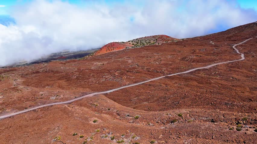 Aerial view of the rugged volcanic terrain and winding dirt road on Mauna Kea in Hawaii County, Hawaii, United States.